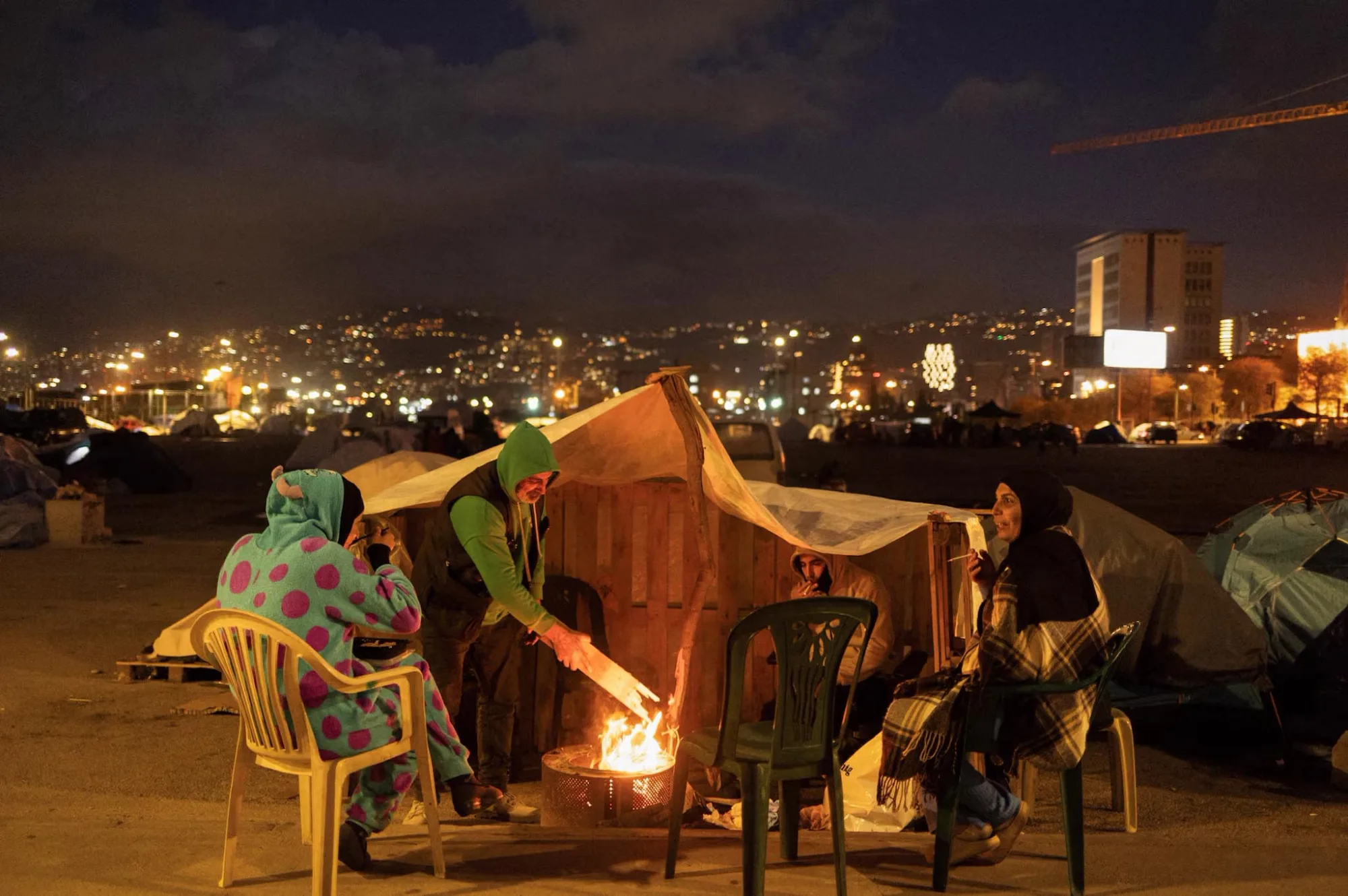 Una familia se sienta junto a una hoguera frente a su tienda de campaña, en un campamento provisional para personas desplazadas, en Beirut (Líbano), el 30 de marzo. Créditos: Reuters/Adnan Abidi