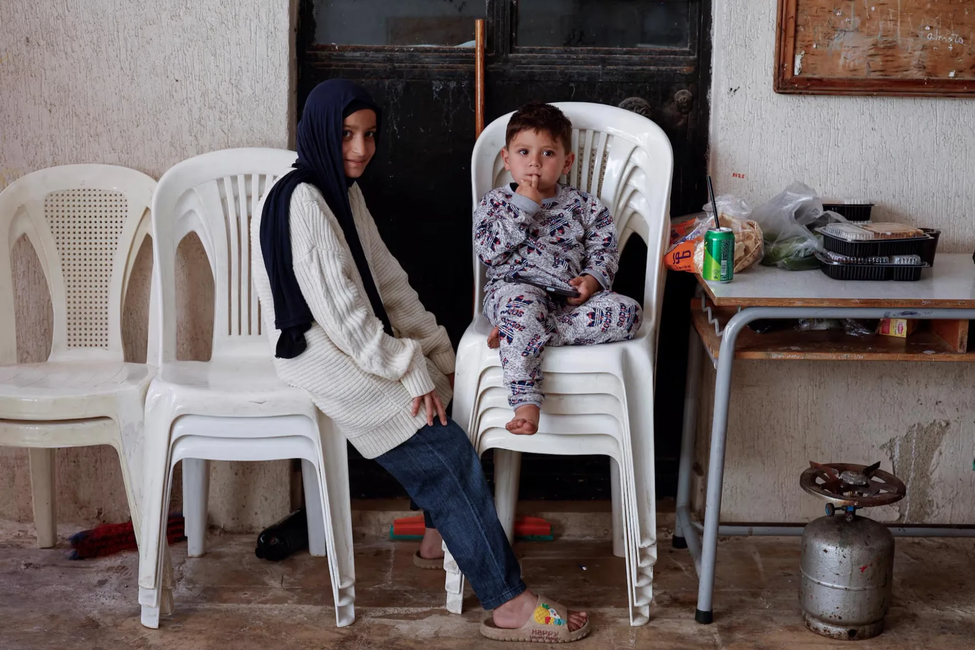 Unos niños sentados en el patio de un instituto femenino, convertido en centro de acogida para personas desplazadas, en Tiro (Líbano), el 12 de abril. Créditos: Reuters/Louisa Gouliamaki