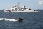 Personal del Servicio de Guardacostas de Filipinas en un bote inflable pasando rápidamente junto a un patrullero de la Guardia Costera de China cerca de un banco de arena disputado en el Mar del Sur de China en abril. Crédito... Ted Aljibe/Agence France-Presse — Getty Images