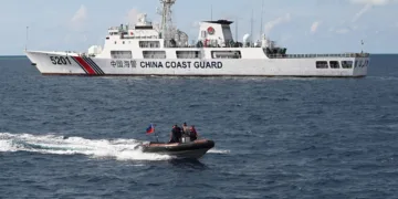 Personal del Servicio de Guardacostas de Filipinas en un bote inflable pasando rápidamente junto a un patrullero de la Guardia Costera de China cerca de un banco de arena disputado en el Mar del Sur de China en abril. Crédito... Ted Aljibe/Agence France-Presse — Getty Images