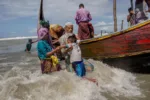 Un anciano musulmán rohingya ayuda a un niño a bajar de una embarcación tras llegar de Myanmar a Bangladés el 14 de septiembre. Créditos: Dar Yasin—AP
