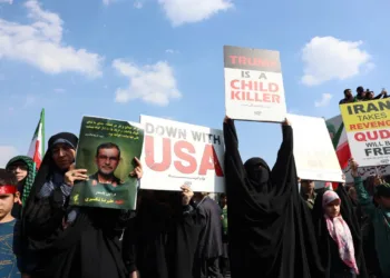 Una mujer sostiene un retrato de Alireza Tangsiri y carteles contra Estados Unidos durante su funeral. Créditos: AFP/ Aljazeera.