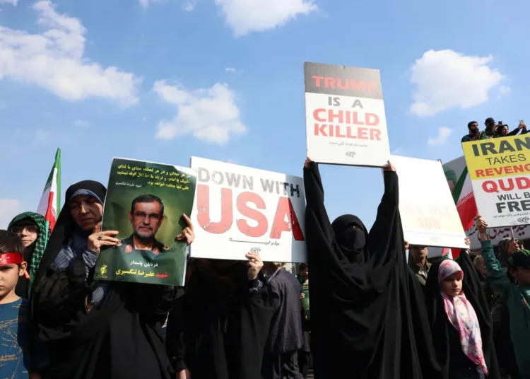 Una mujer sostiene un retrato de Alireza Tangsiri y carteles contra Estados Unidos durante su funeral. Créditos: AFP/ Aljazeera.