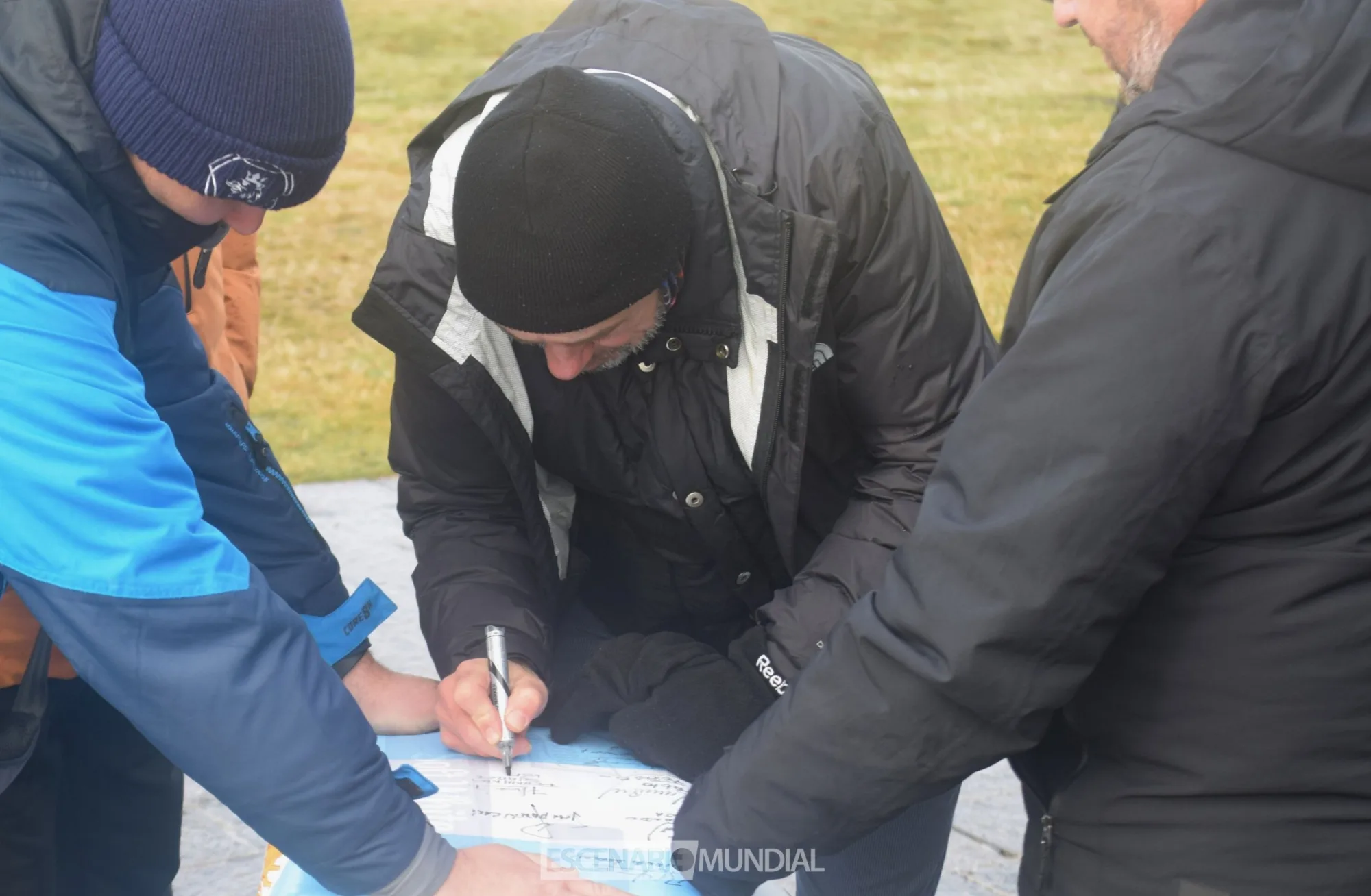 Fernando Suarez firma una bandera argentina que se dejó como recuerdo en el Cementerio de Darwin. Crédito: Alejo Sanchez Piccat / Escenario Mundial