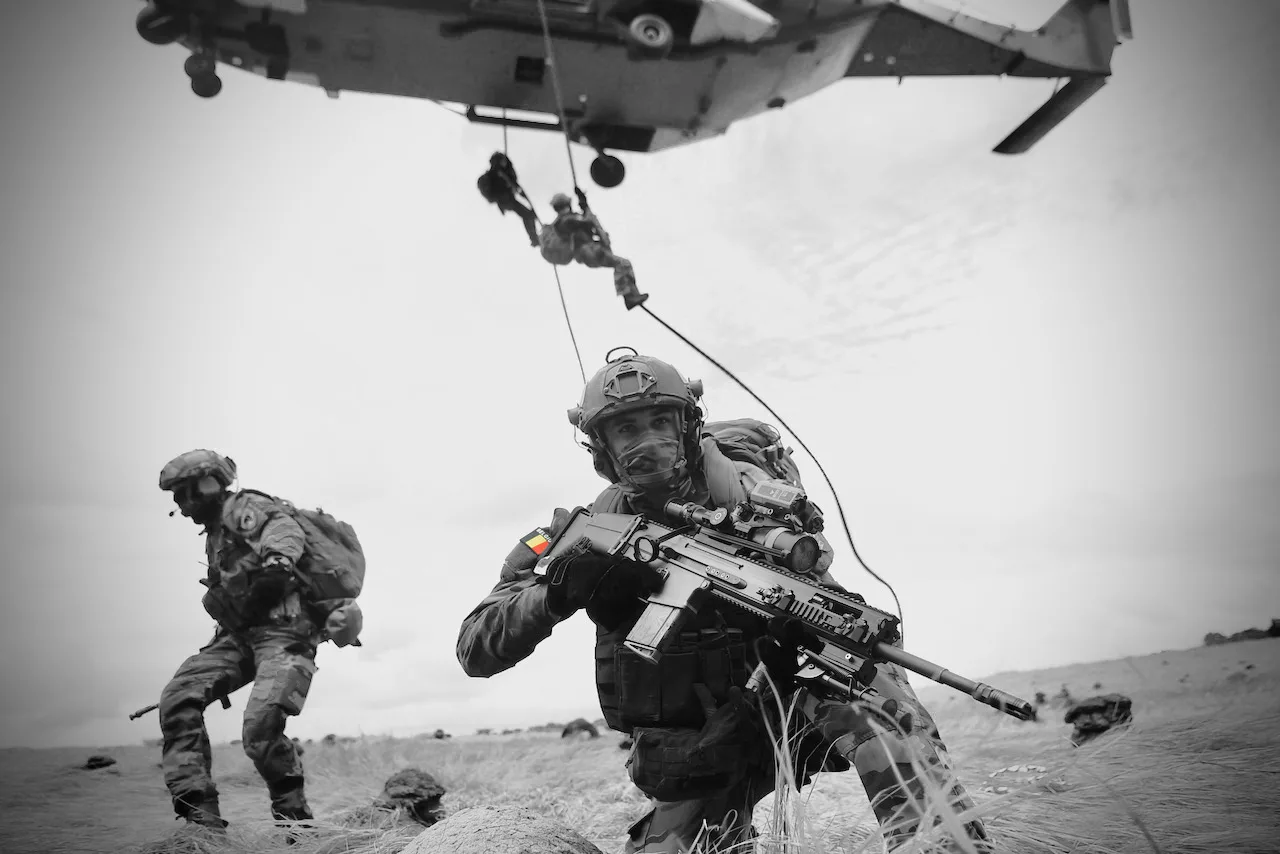 Soldados belgas equipados con armamento moderno y un helicóptero en operación. Créditos: Mando Terrestre Aliado de la OTAN.