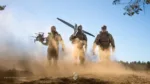 Soldados ucranianos equipados con drones (uno multicóptero y uno de ala fija) avanzando en un entorno polvoriento, subrayando capacidades modernas de combate. Créditos: Ministerio de Defensa de Ucrania.