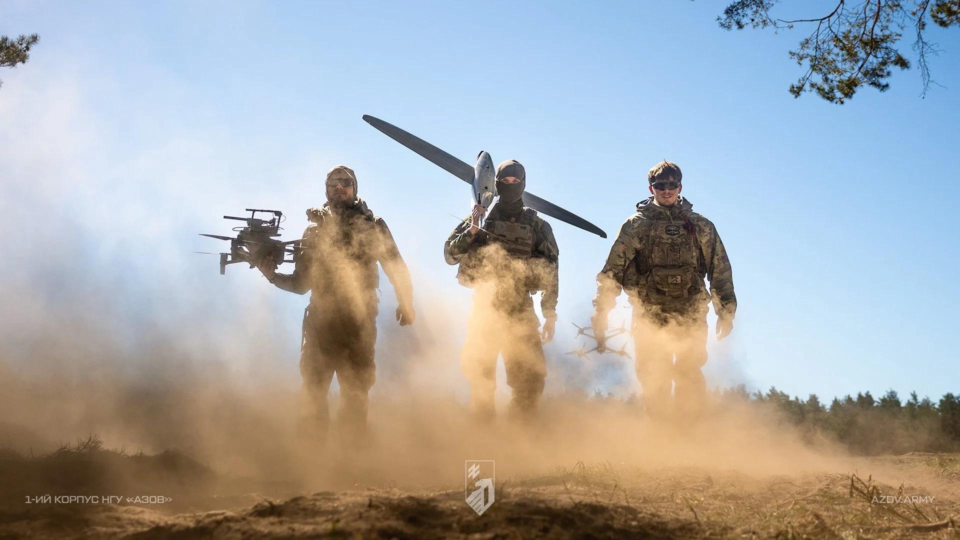 Soldados ucranianos equipados con drones (uno multicóptero y uno de ala fija) avanzando en un entorno polvoriento, subrayando capacidades modernas de combate. Créditos: Ministerio de Defensa de Ucrania.