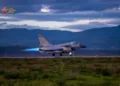 Un caza J-10 despegando en pista con postquemador encendido (llama azul), fondo montañoso con turbinas eólicas. Pertenece a una brigada de aviación de la Fuerza Aérea del Comando Sur del EPL. Créditos: China Military Bugle.