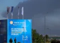 Agentes de policía se encuentran frente a un cartel y banderas con el logotipo del Foro Económico Internacional de San Petersburgo (SPIEF), mientras una densa humareda se eleva al fondo tras el impacto de drones en infraestructura, según informó el gobernador Alexander Beglov, en San Petersburgo, Rusia, el 3 de junio de 2026. REUTERS/Stringer