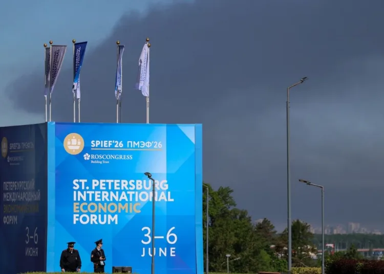 Agentes de policía se encuentran frente a un cartel y banderas con el logotipo del Foro Económico Internacional de San Petersburgo (SPIEF), mientras una densa humareda se eleva al fondo tras el impacto de drones en infraestructura, según informó el gobernador Alexander Beglov, en San Petersburgo, Rusia, el 3 de junio de 2026. REUTERS/Stringer