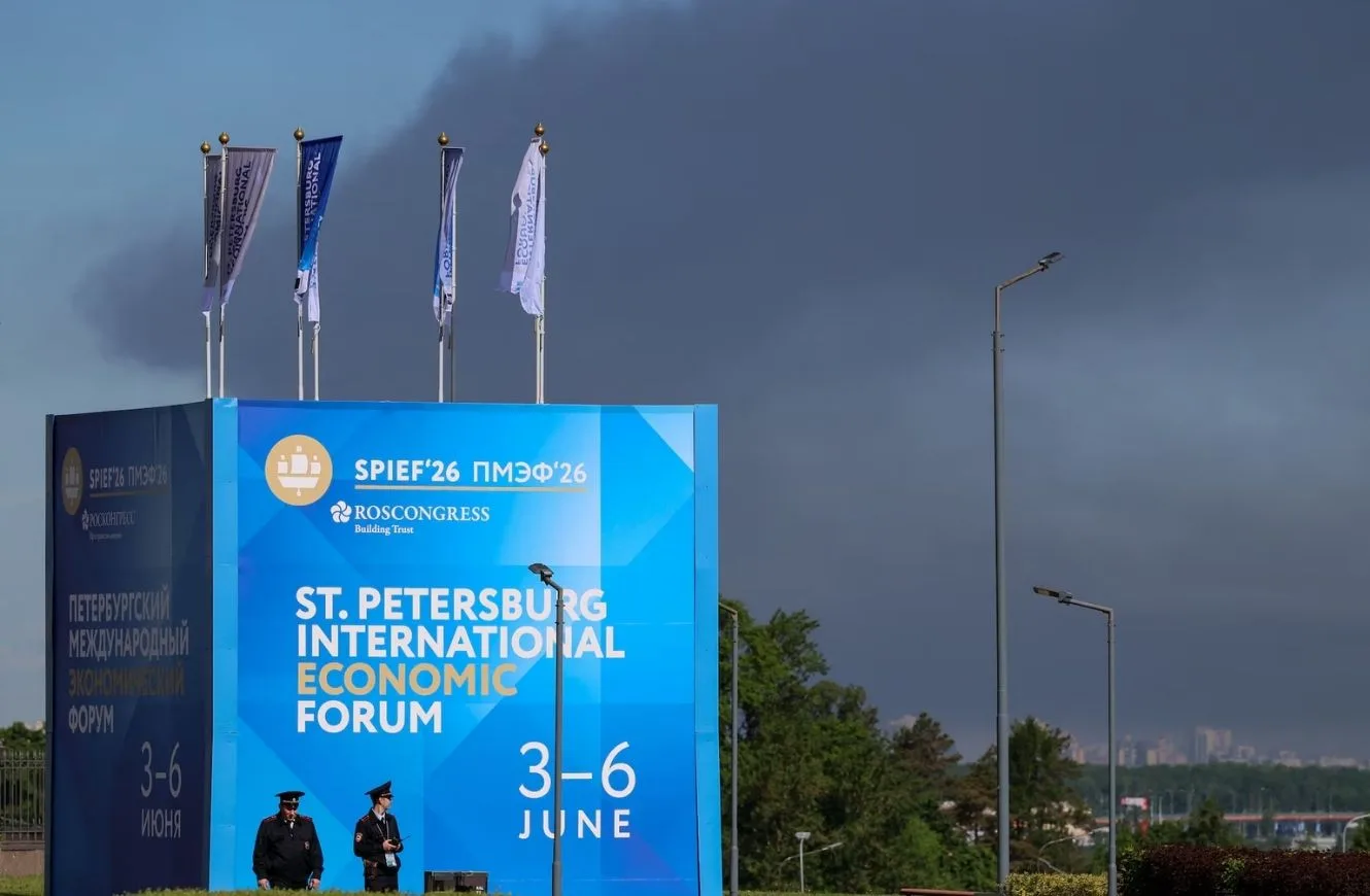 Agentes de policía se encuentran frente a un cartel y banderas con el logotipo del Foro Económico Internacional de San Petersburgo (SPIEF), mientras una densa humareda se eleva al fondo tras el impacto de drones en infraestructura, según informó el gobernador Alexander Beglov, en San Petersburgo, Rusia, el 3 de junio de 2026. REUTERS/Stringer