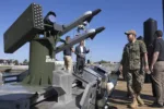 Sistema de lanzamiento de misiles o cohetes SNC BRAVE montado en una plataforma naval o muelle, con personal militar observando (incluyendo Marines). Créditos: U.S. Naval Forces Southern Command and U.S. 4th Fleet.