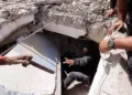 Una persona le entrega un martillo a un hombre mientras registran los escombros de un edificio en La Guaira, Venezuela, el 25 de junio. Créditos: Reuters.
