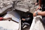 Una persona le entrega un martillo a un hombre mientras registran los escombros de un edificio en La Guaira, Venezuela, el 25 de junio. Créditos: Reuters.