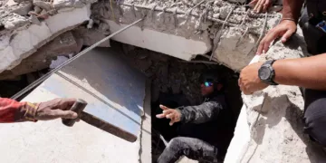 Una persona le entrega un martillo a un hombre mientras registran los escombros de un edificio en La Guaira, Venezuela, el 25 de junio. Créditos: Reuters.