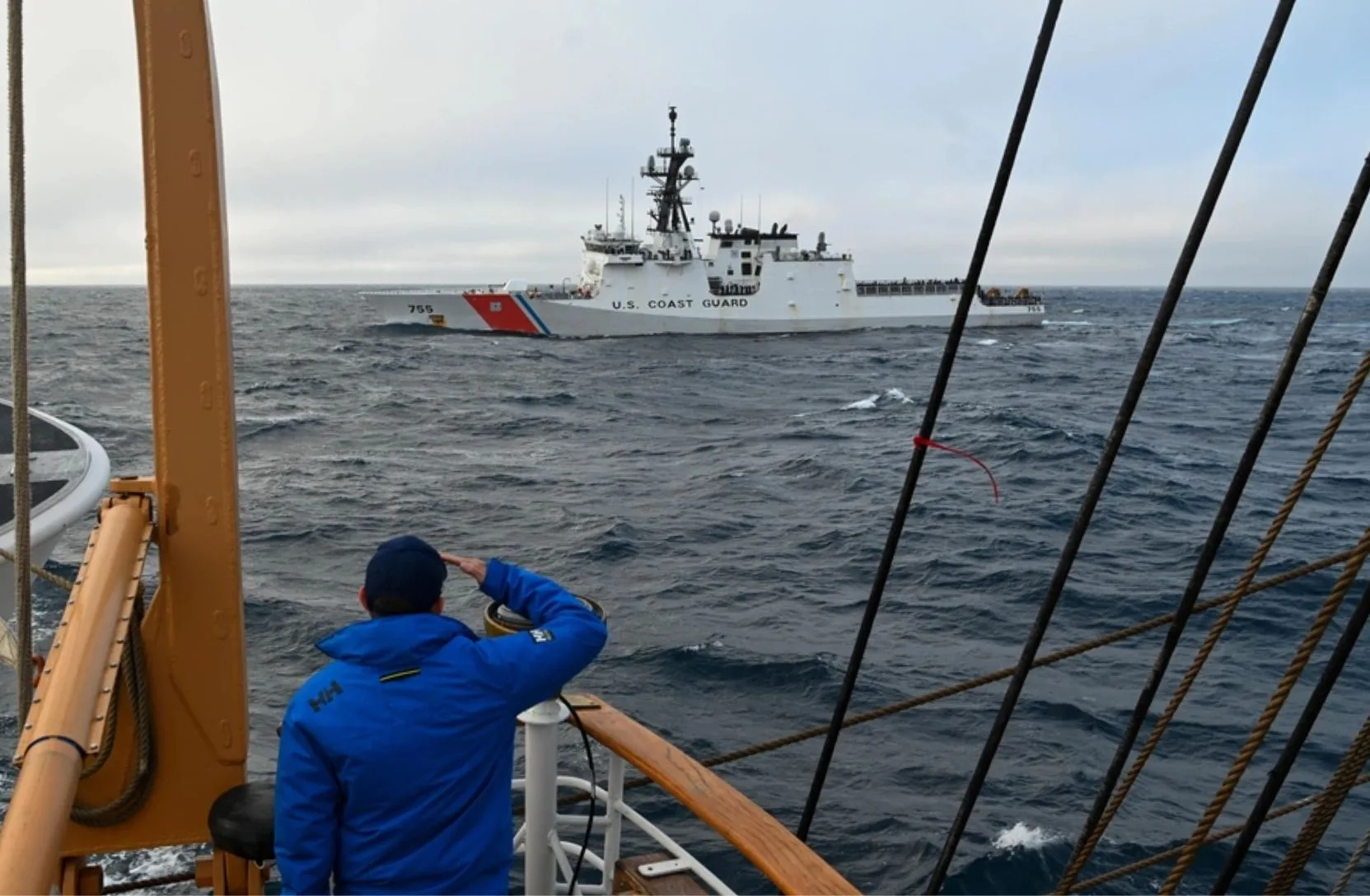 El Capitán de la Guardia Costera de EE. UU., Kristopher Ensley, saluda al Guardacostas Munro (WMSL 755) mientras navega a bordo del Guardacostas Eagle (WIX 327) en el Estrecho de Juan de Fuca, el 13 de julio de 2025. Los honores de paso son una costumbre observada cuando los buques militares pasan en proximidad cercana entre sí. (Foto de la Guardia Costera de EE. UU. por el Oficial de Tercera Clase Nicholas Strasburg)