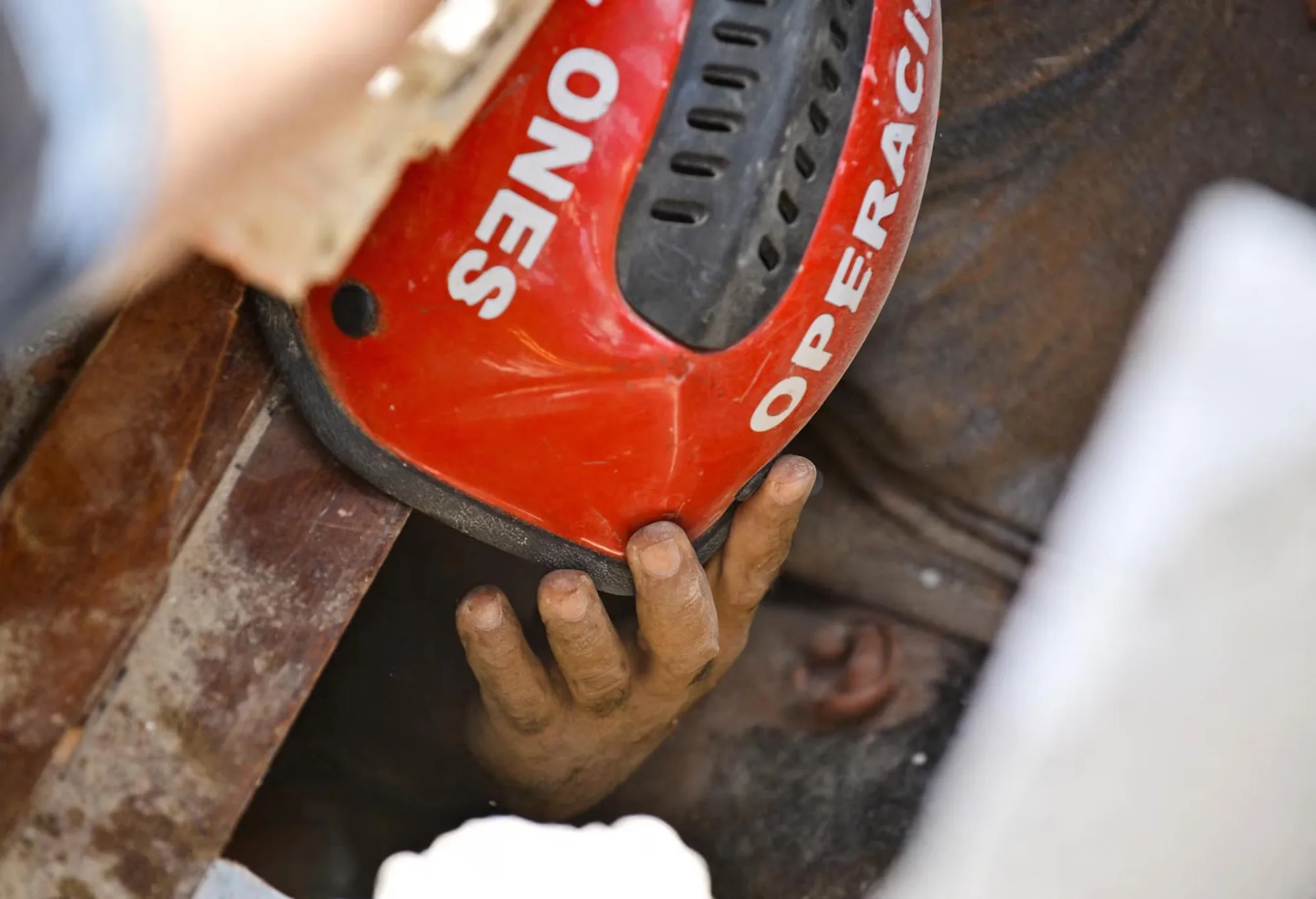 Héctor López se pone el casco que le han dado para protegerse la cabeza mientras varias personas intentan sacarlo de debajo de los escombros de un edificio derrumbado en La Guaira, Venezuela, el 25 de junio. Créditos: Reuters.