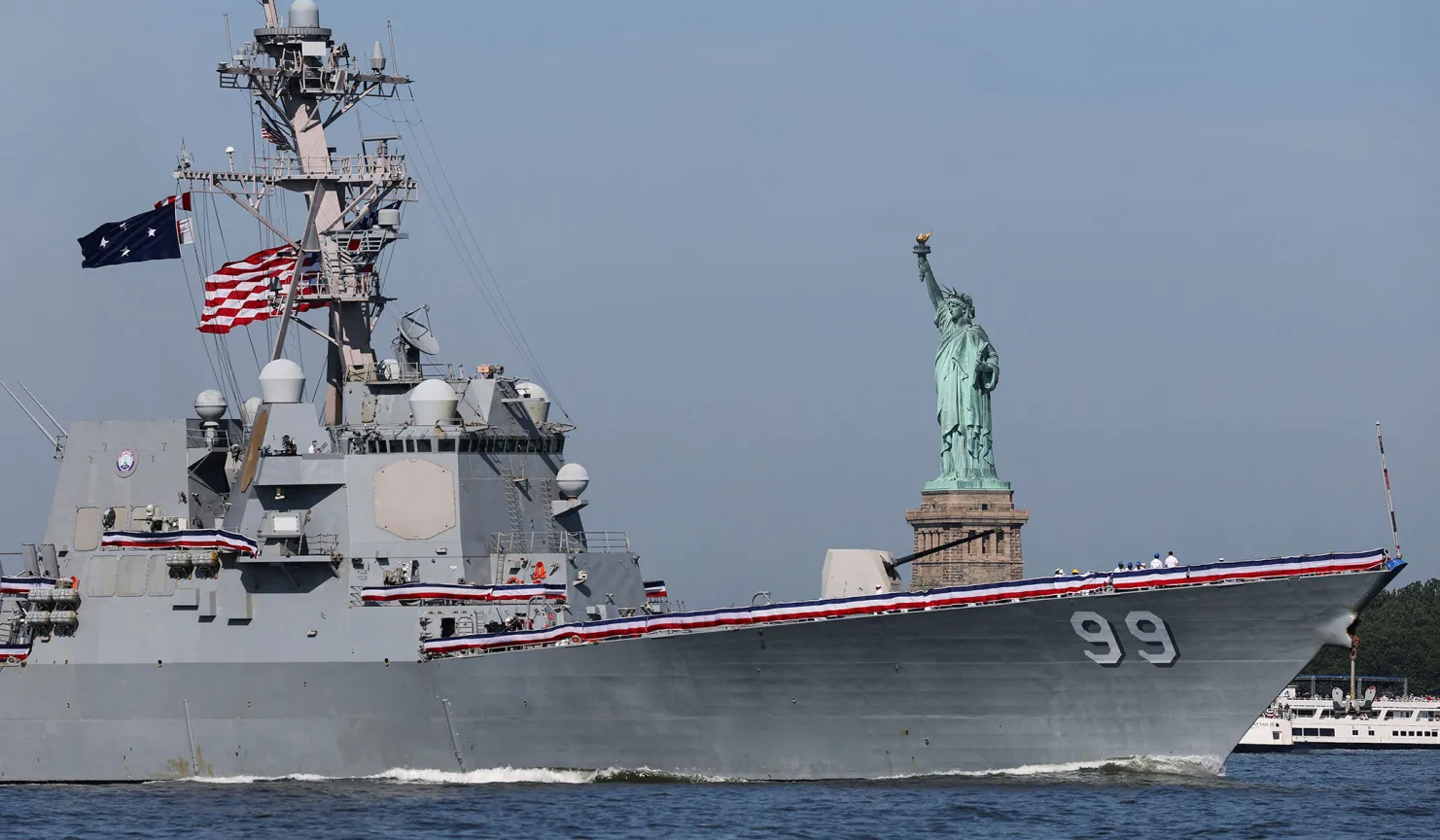 El destructor de misiles guiados de la clase Arleigh Burke de la Marina de los EE. UU., Farragut (DDG-99), pasa junto a la Estatua de la Libertad durante el desfile de barcos Sail 250, mientras Estados Unidos celebra su 250 aniversario el Día de la Independencia en el puerto de Nueva York, el 4 de julio de 2026. Carlos Barria/Reuters