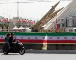 Una pareja iraní pasa en motocicleta frente a misiles iraníes, Zolfaghar, exhibidos en la Plaza Azadi en Teherán. Fotografía: Abedin Taherkenareh/EPA