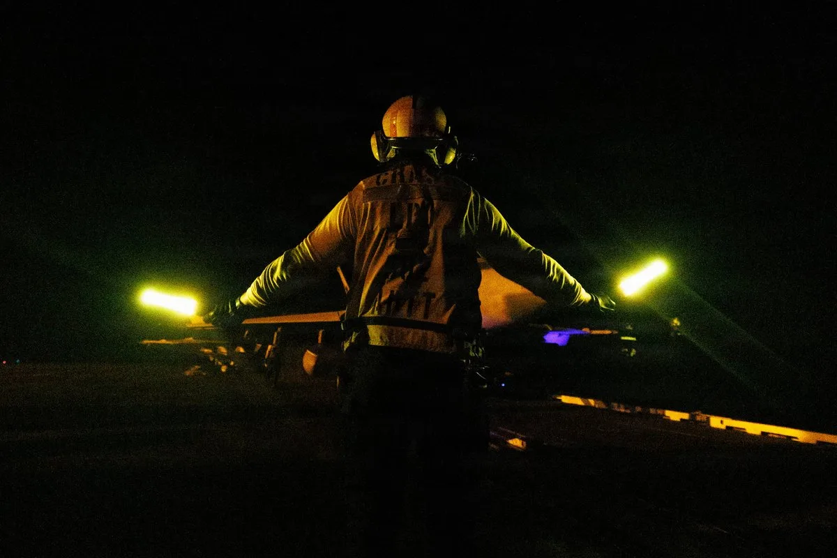 CENTCOM muestra marineros de EE.UU. realizando operaciones de vuelo nocturno en el portaaviones USS George H.W. Bush (CVN 77) durante su tránsito por el Mar Arábigo, con imágenes de personal de cubierta dirigiendo aeronaves en condiciones de baja visibilidad. Créditos: CENTCOM.