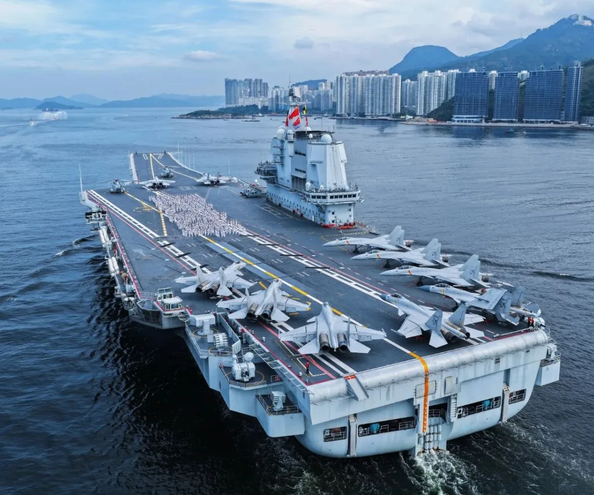 El portaaviones Shandong (CV-17) de la Armada de China navega rumbo a Hong Kong con dotación militar formada en cubierta y cazas Shenyang J-15 desplegados en la pista