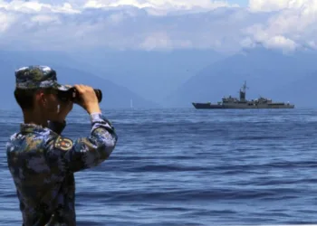 Soldado del Ejército Popular de Liberación (EPL) mira a través de unos prismáticos, durante unas maniobras militares, con la fragata taiwanesa Lan Yang de fondo, el 5 de agosto de 2022