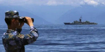Soldado del Ejército Popular de Liberación (EPL) mira a través de unos prismáticos, durante unas maniobras militares, con la fragata taiwanesa Lan Yang de fondo, el 5 de agosto de 2022