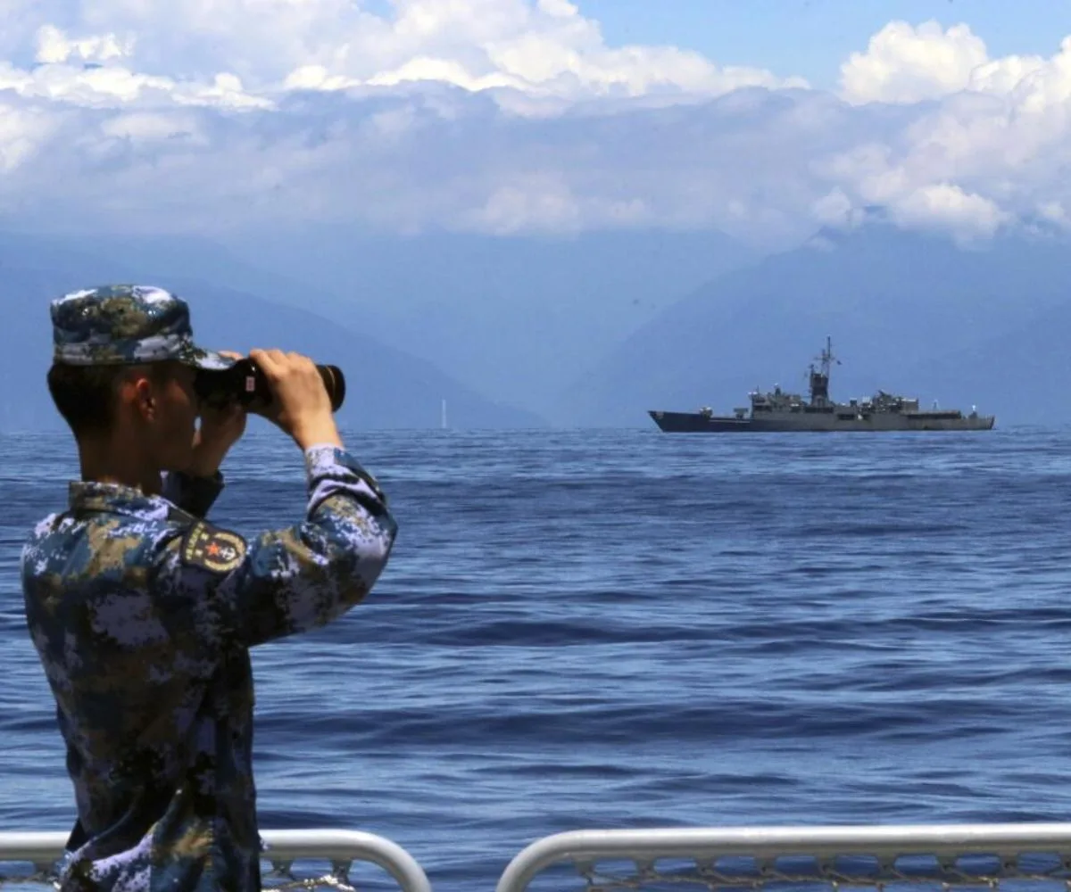 Soldado del Ejército Popular de Liberación (EPL) mira a través de unos prismáticos, durante unas maniobras militares, con la fragata taiwanesa Lan Yang de fondo, el 5 de agosto de 2022