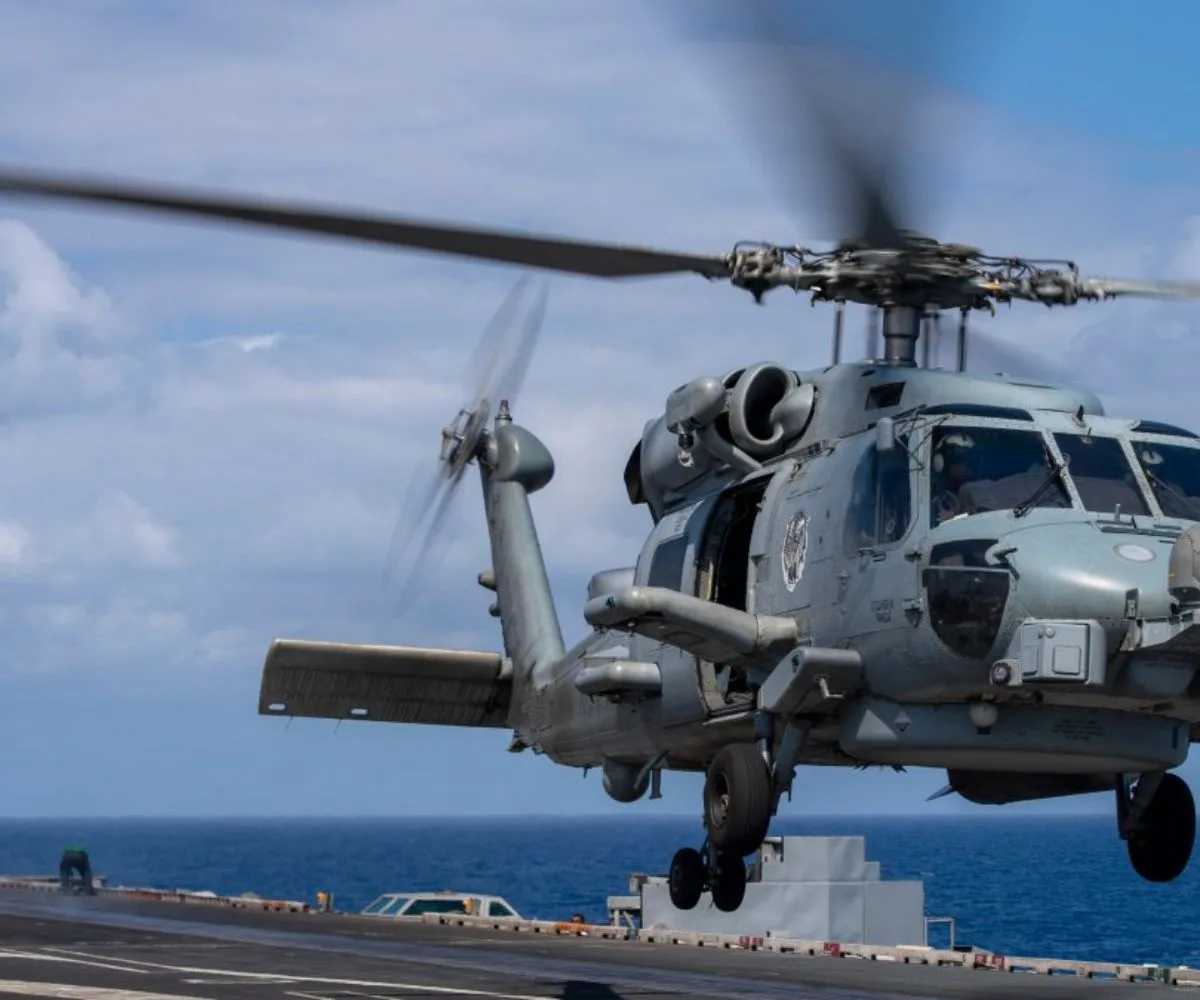 Un helicóptero militar realiza maniobras de aproximación sobre la cubierta de un portaaviones en alta mar, como parte de operaciones aéreas. Imagen ilustrativa.