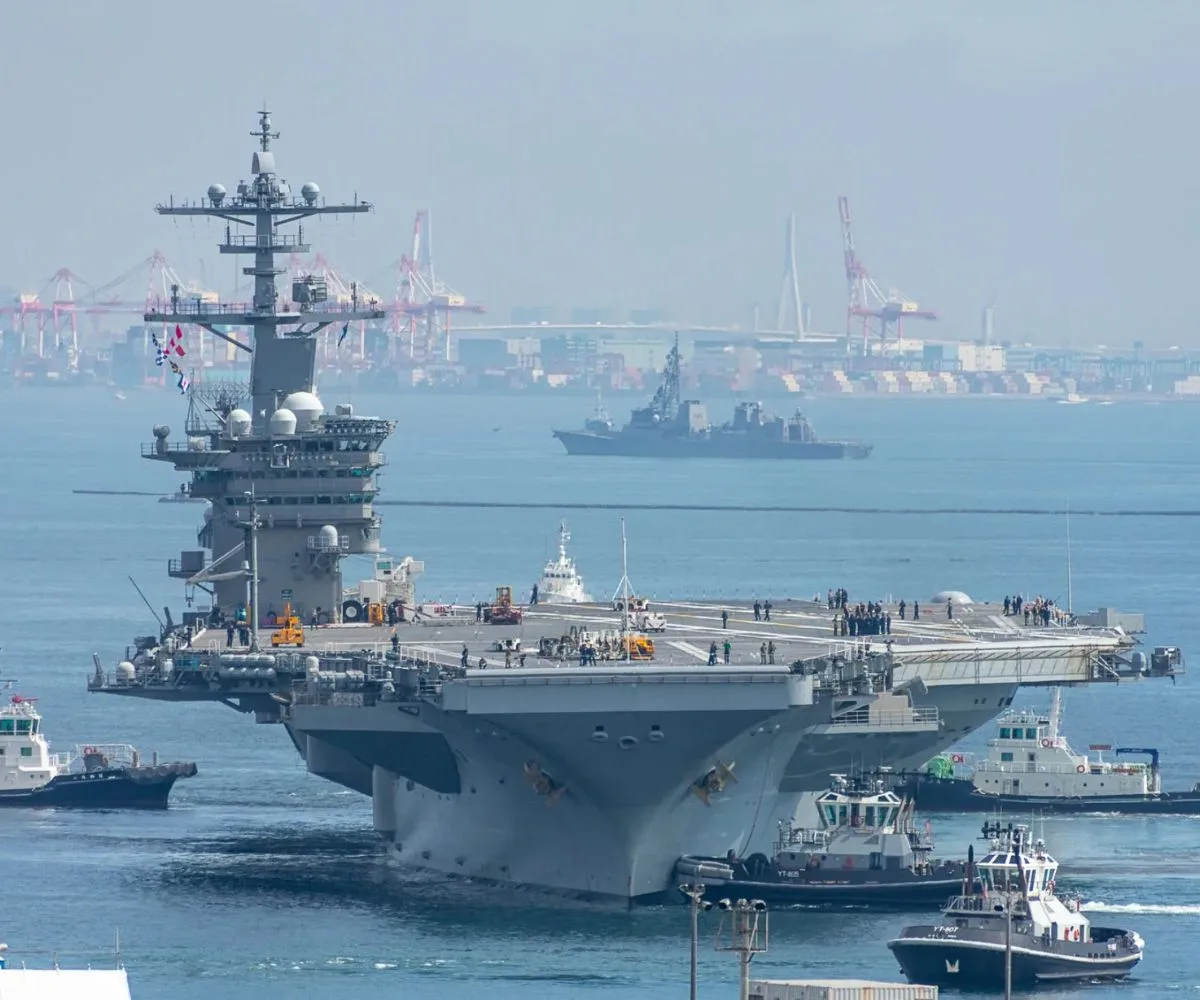 El portaaviones de propulsión nuclear USS George Washington navega frente a una zona portuaria, acompañado por embarcaciones de apoyo, en el Pacífico
