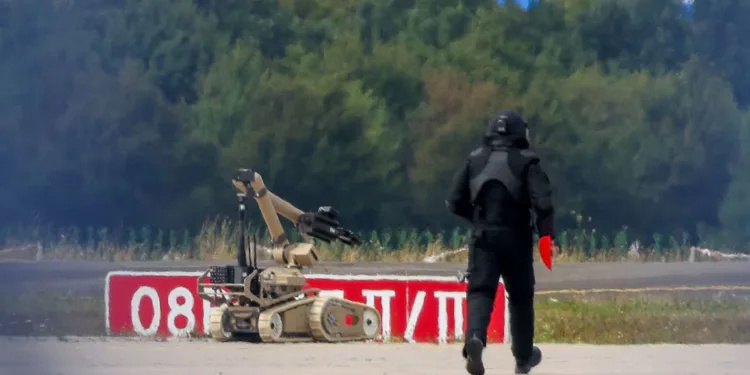 Un agente de policía con equipo de protección camina junto a un robot de desactivación de explosivos (EOD) en el aeropuerto de Leipzig/Halle, en Schkeuditz (Alemania), el 5 de agosto de 2026. Créditos. Axel Schmidt