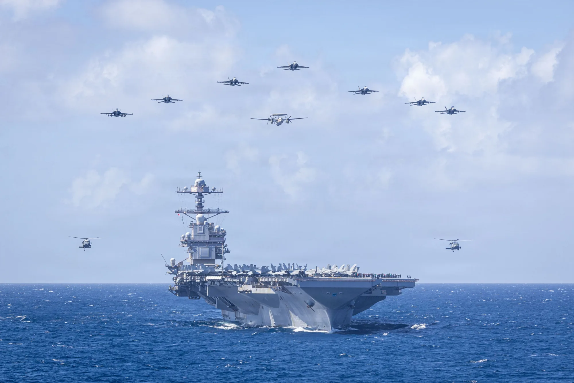 Aviones del Ala Aérea de Portaaviones 8 de la Marina de EE. UU. vuelan en formación sobre el portaaviones más grande del mundo, el portaaviones de clase Ford USS Gerald R. Ford (CVN 78), durante la ceremonia aérea de cambio de mando del Ala Aérea de Portaaviones 8 mientras navega en el Mar Caribe. Créditos: Armada de los EE.UU.
