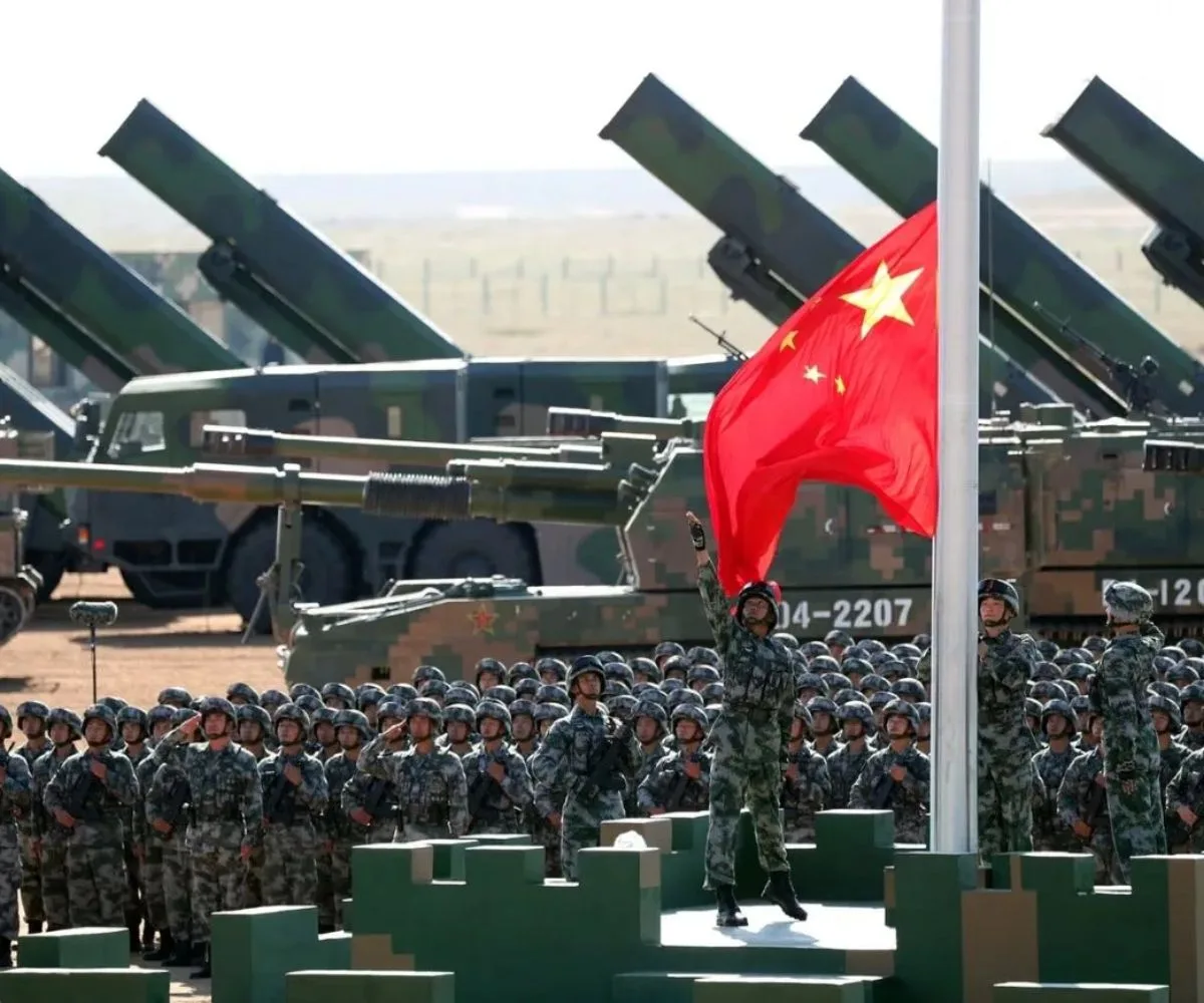 Soldados del Ejército Popular de Liberación (EPL) de China rinden honores militares, durante el izado de la bandera nacional en una base de entrenamiento