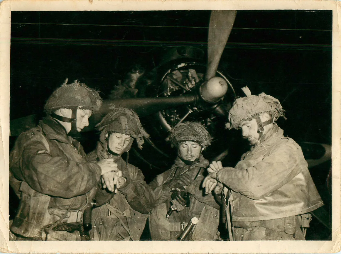 Soldados británicos de la 6º División Aerotransportada sincronizando sus relojes frente a un avión antes del salto en Normandía en 1944. Créditos: Ejército Británico.