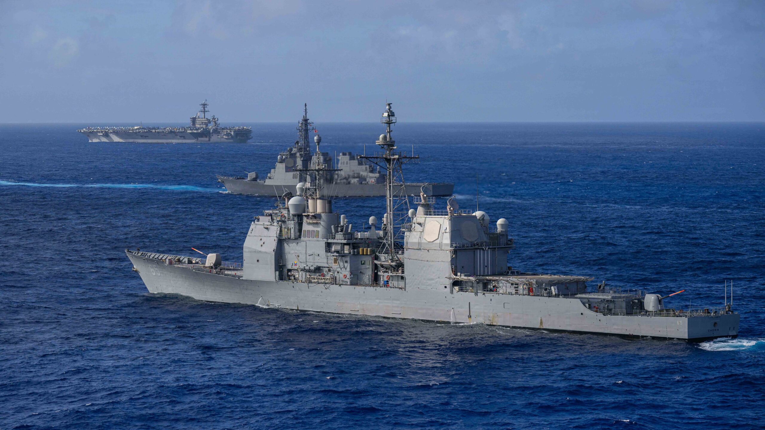 El crucero de misiles guiados de la clase Ticonderoga USS Chosin (CG 65), al frente, el destructor de misiles guiados de la clase Kongo de la Fuerza Marítima de Autodefensa de Japón JS Kongo (DDG 173), en el centro, y el portaaviones de la clase Nimitz USS Theodore Roosevelt (CVN 71) navegan en formación durante el ejercicio Keen Sword 27 (KS27), el 21 de octubre de 2026 en el Mar de Filipinas. Créditos: DVIDS.