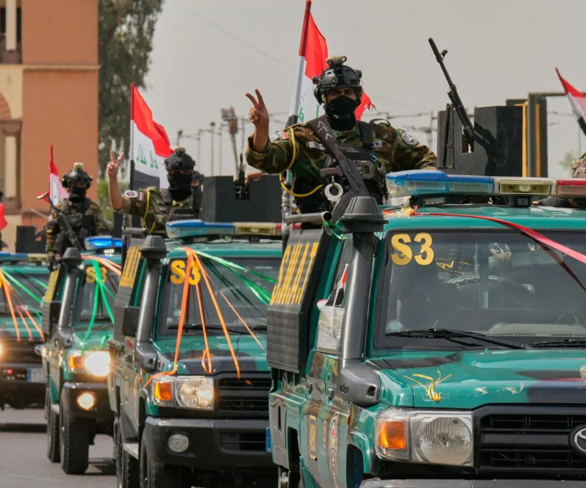 Agentes de las fuerzas de seguridad iraquíes hacen el signo de la victoria con mano mientras circulan en vehículos decorados con banderas y lazos en una caravana que conmemora la finalización de la retirada de las tropas estadounidenses de Irak, Bagdad, Irak, el 30 de septiembre de 2026