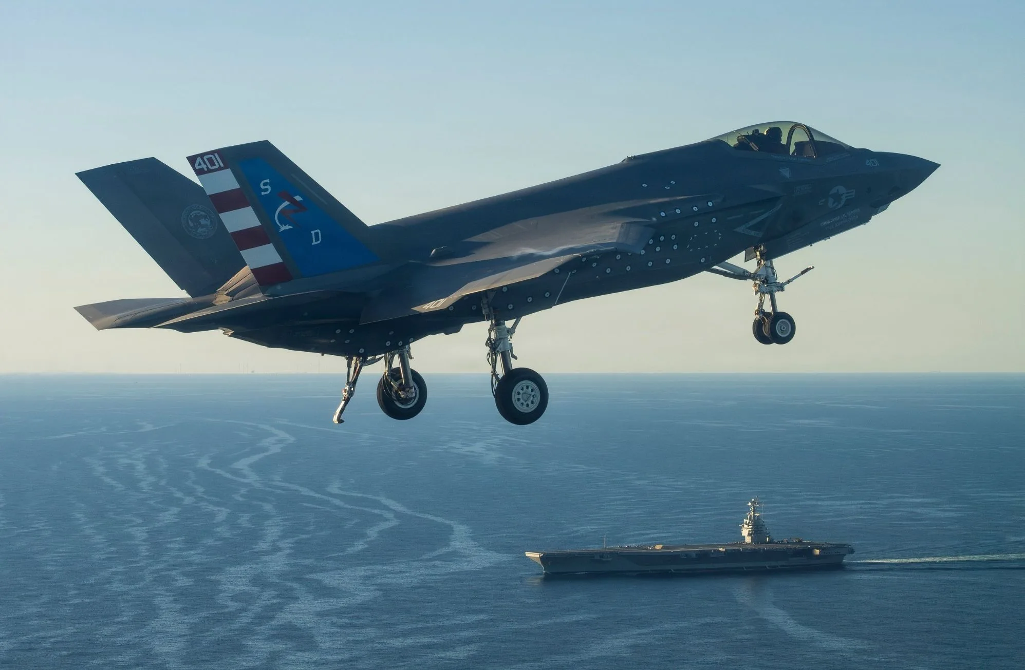 Un piloto de pruebas de F-35 del Escuadrón de Pruebas y Evaluación Aérea Dos Tres (VX-23), División de Aeronaves del Centro de Guerra Aérea Naval (NAWCAD), pilota un caza F-35C Lightning II hacia la PCU John F. Kennedy (CVN 79) en el Atlántico Occidental el 13 de octubre de 2026.
