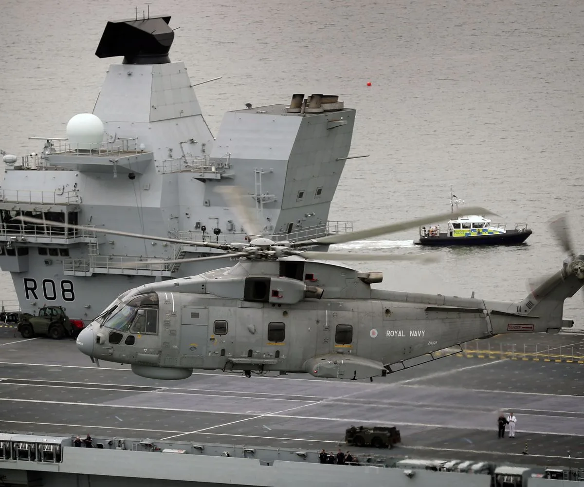 Un helicóptero AgustaWestland Merlin HM2 del Escuadrón Aéreo Naval 820 de la Royal Navy sobrevuela el portaaviones HMS Queen Elizabeth (R08) durante las pruebas de mar frente a la costa de Escocia, el 26 de junio de 2017. Imagen ilustrativa